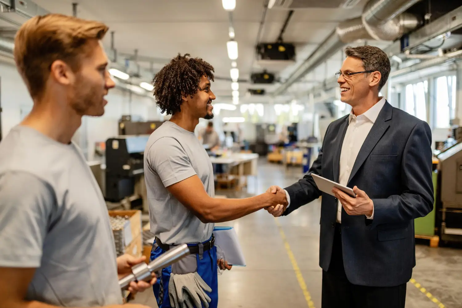 Business professional shaking hands with factory workers